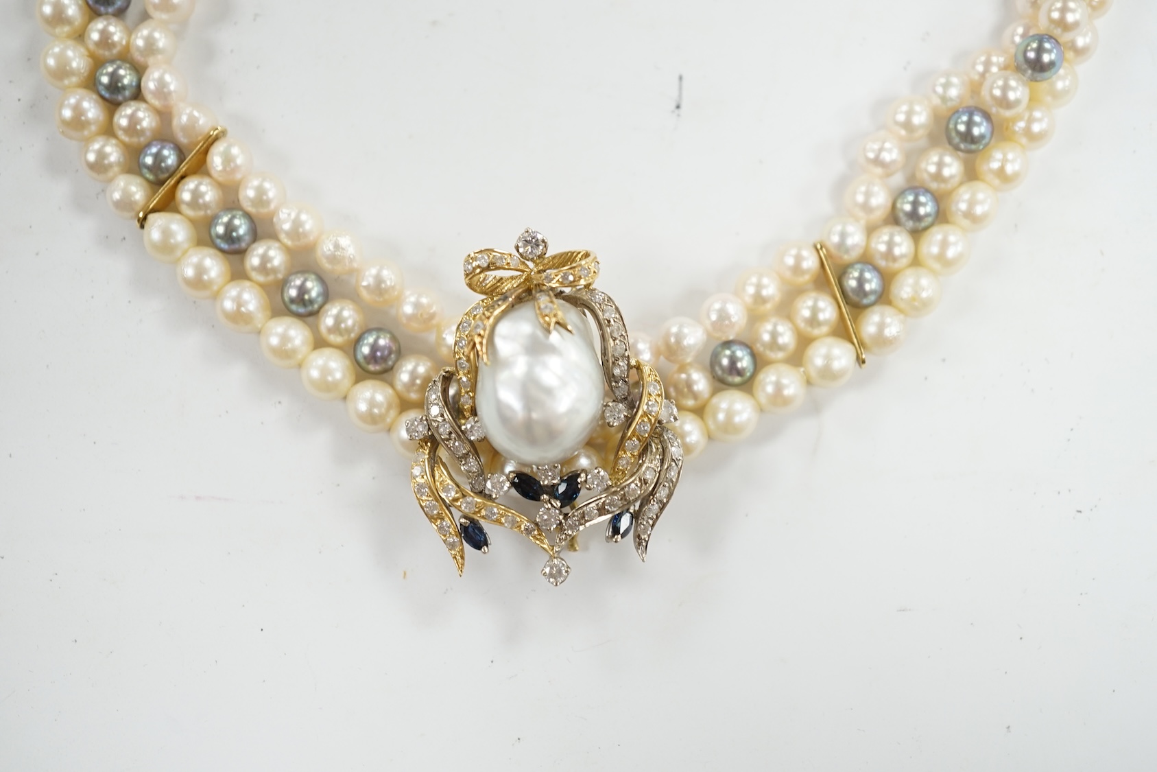 A modern triple strand two colour cultured pearl necklace, with yellow metal clasp and detachable yellow metal baroque pearl, sapphire and diamond cluster set clip, 43cm, gross weight 101.9 grams. Condition - fair to goo